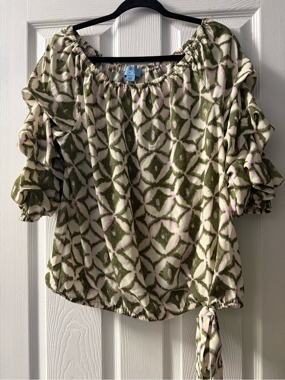 CeCe blouse features a green and white geometric pattern with ruffled sleeves